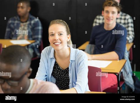 View Of Smiling Students Sitting At Desks In Classroom Stock Photo Alamy