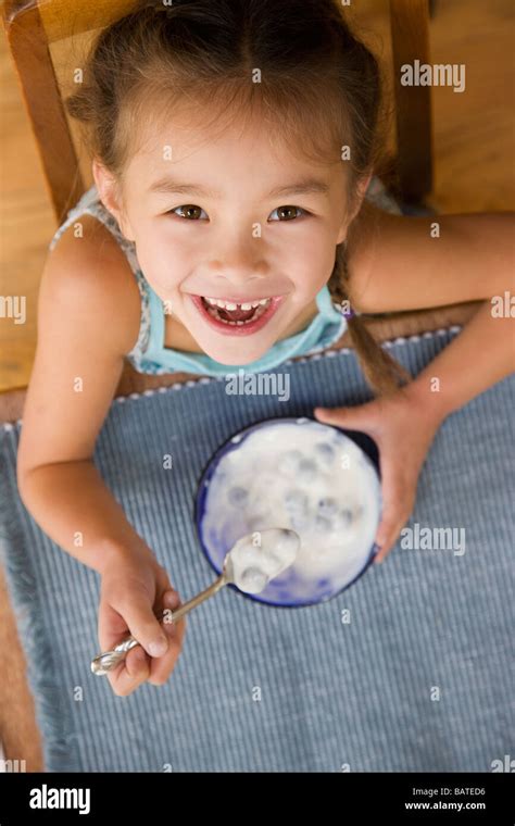 Mixed Race Young Girl Eating Yogurt With Spoon Stock Photo Alamy