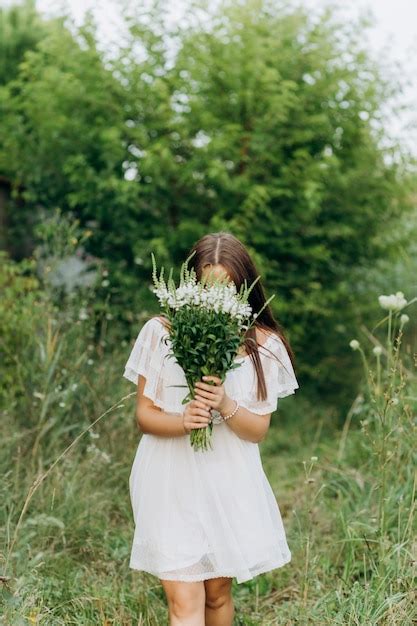 Premium Photo Beautiful Young Brunette Woman Holding Bouquet Of Wildflowers In Summer