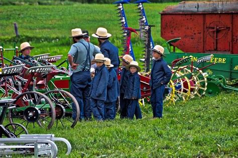 A Group Of Men Standing Next To Each Other In Front Of Farm Equipment