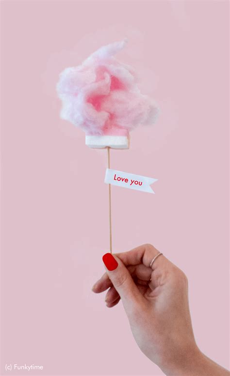 a hand holding a cotton candy lollipop with the words love you on it