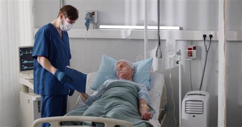 Sick Aged Man Lying In Hospital Bed And Signing Medical Document Stock