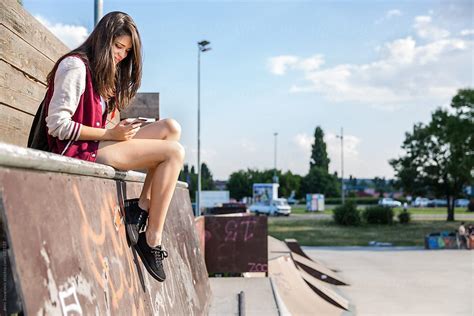 Ver Girl Sitting In A Skate Park Checking Her Phone Del Colaborador De Stocksy Jovo Jovanovic