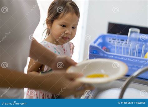 A Mother Teaching Her Child How To Wash Dishes At Home Stock Image
