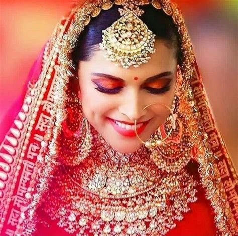 a woman wearing a red and gold bridal outfit with her eyes closed to the side
