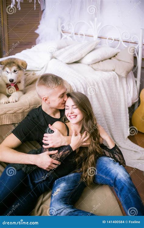 Joyful Young Loving Couple Sitting In The Bedroom While Expressing Love
