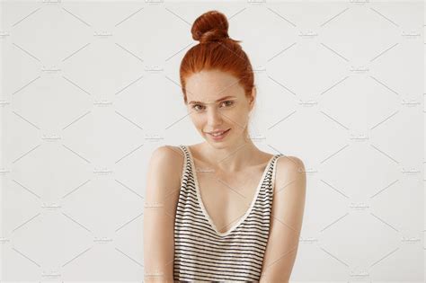 Pretty Female With Red Hair Tied In Bun Looking Shamefacedly Into