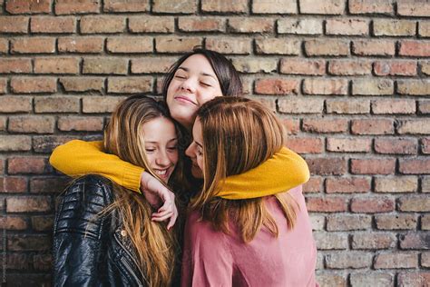 Teen girls embracing together in front of a brick wall. by BONNINSTUDIO - Friend - Stocksy United