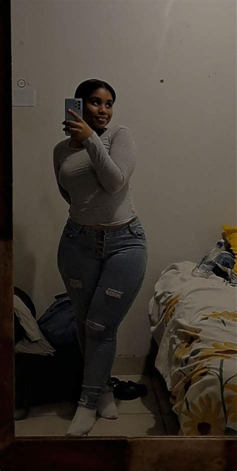 A Woman Is Taking A Selfie In Her Bedroom While Wearing Ripped Jeans