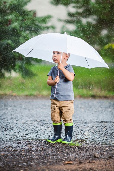 adorable child holding  umbrella   rain storm stock photo  tommyandone