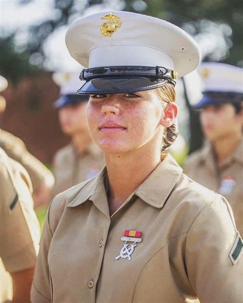 A Woman In Uniform Standing Next To Other Uniformed People And Looking Off Into The Distance