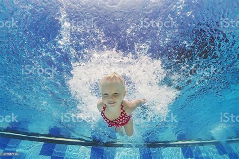 Child Swimming Underwater With Splashes In The Pool Stock Photo