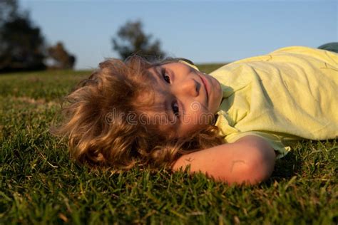 Portrait Of A Smiling Child Lying On Green Grass Cute Kid Boy Enjoying