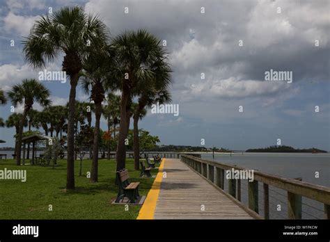 A Waterside Walkway Separates The Palm Trees From The Waters Of The St