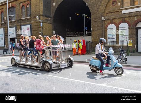 Hen Party On A Pedibus Following A Smartly Dressed Man On A Scooter In