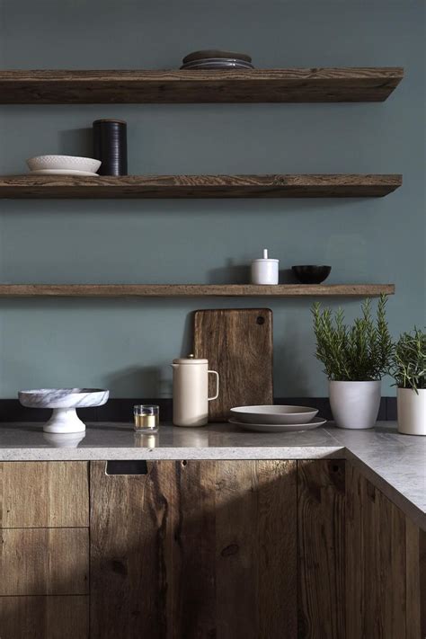 Gray grounds a lot of other elements in your kitchen like your kitchen appliance colors and any natural materials you might have such as stone countertops and exposed wood. Dark wood kitchen cabinetry with moody grey green walls and matching dark wood floating shelving ...