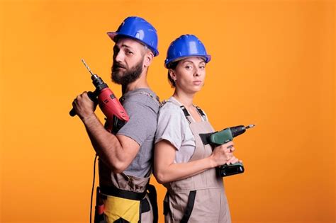 premium photo construction workers posing with electric power drills looking at camera and