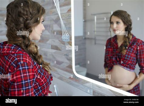A Pregnant Woman In The Bathroom Looking In The Mirror Female Dressed