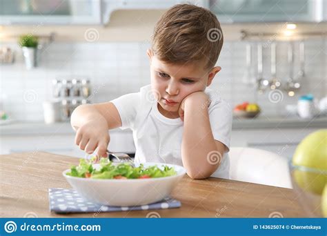 Unhappy Little Boy Eating Vegetable Salad At Table Stock Photo Image