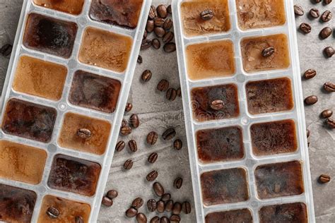 Ice Cubes In Trays And Coffee Beans On Grey Background Stock Photo