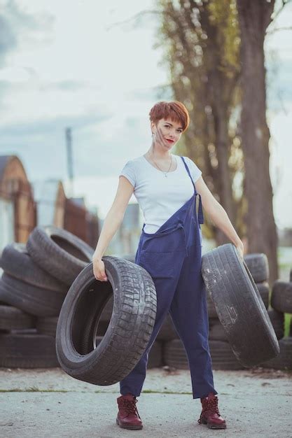 Premium Photo Attractive Woman Mechanic In Overalls Holding Tires