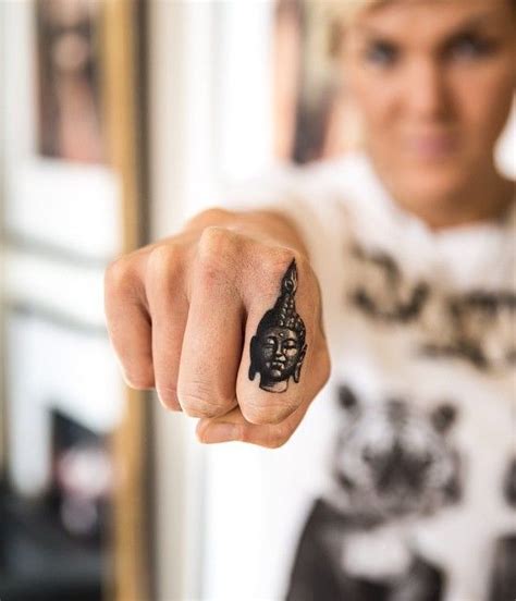A Woman Pointing Her Finger At The Camera With A Black Ink Tattoo On Her Hand