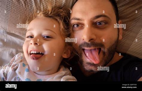 Authentic Close Up Of A Dad And Daughter Making Funny Faces Looking At The Screen For A Selfie