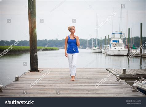 Woman Walking On Dock With Boats In The Background Stock Photo