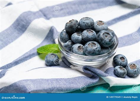 Glass Bowl Full Of Fresh Blueberries With Herbs On Wooden Background