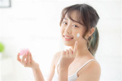 Hermosa Joven Asiática Feliz Aplicando Crema O Loción Con Humectante En La Cara De La Piel