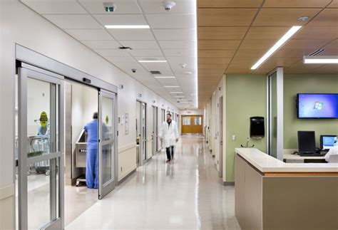 A Doctor In A White Coat Walks Down The Brightly Lit Hallway Of Our Ed