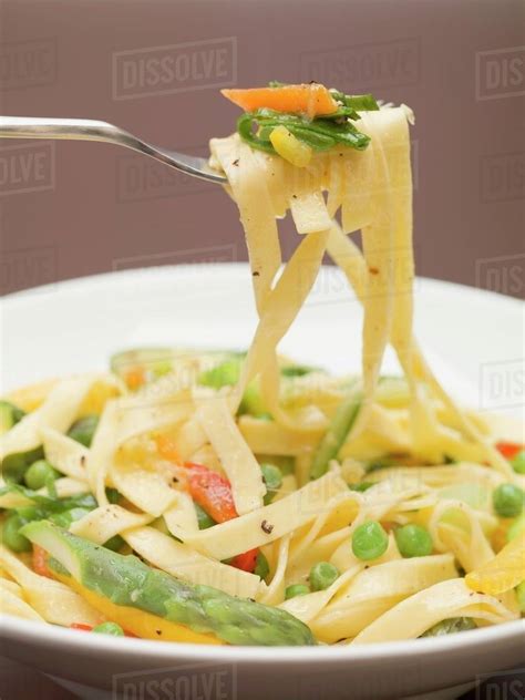 Ribbon Pasta With Vegetables On Fork And Plate Stock Photo Dissolve