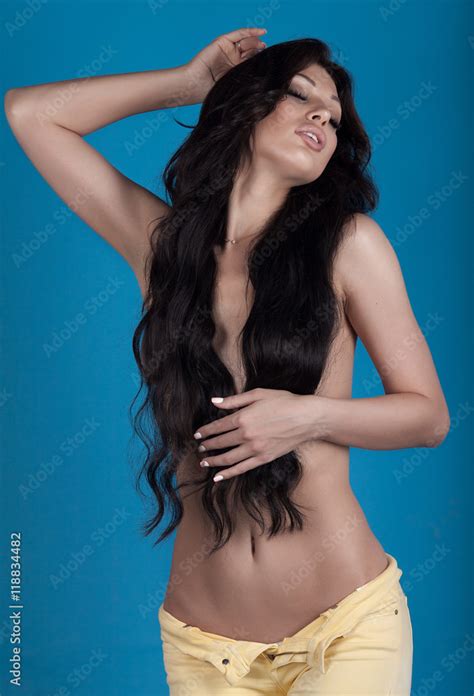 Sexy Naked Woman In Yellow Jeans Long Curly Black Hair On Blue Background Big Boobs Stock