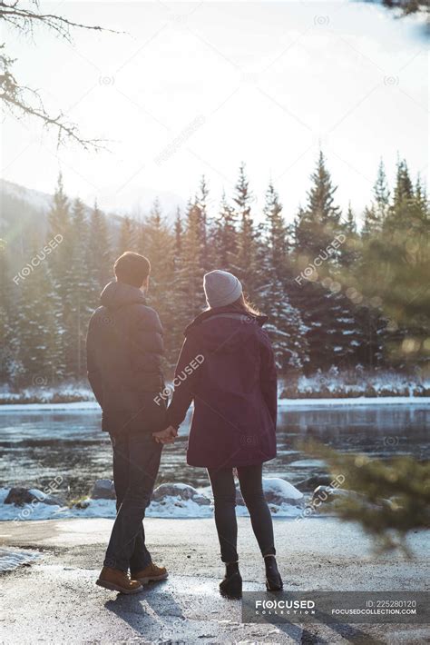 rear view of romantic couple standing by river in winter — female banff national park stock