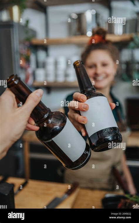 Chef Toasting Beer Bottle With Woman While Standing In Kitchen Stock