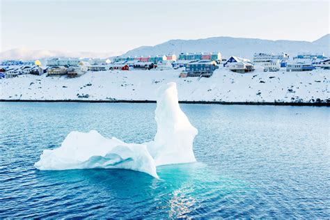 Small Iceberg Floating In The Water In Front Of The Houses Of Nussuaq