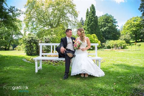 A Bride And Groom Sitting On A White Bench