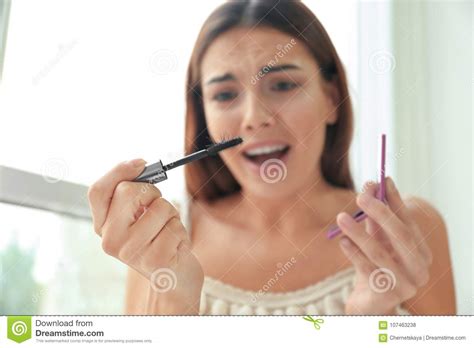 Emotional Young Woman Holding Mascara Brush With Eyelashes Indoors