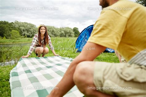 Happy Couple Laying Picnic Blanket At Campsite