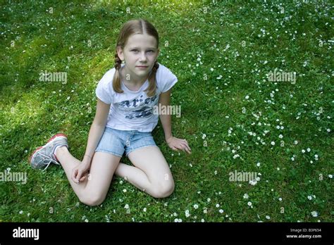 Junges Mädchen Sitzen Auf Wiese Voller Gänseblümchen Stockfotografie