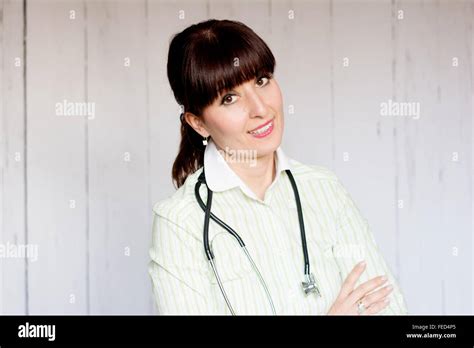 Female Brunette Doctor With Bangs Posing For The Camera Wearing Scrubs And Stethoscope Stock