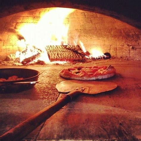 A Pizza Sitting On Top Of A Wooden Spatula In Front Of An Open Oven