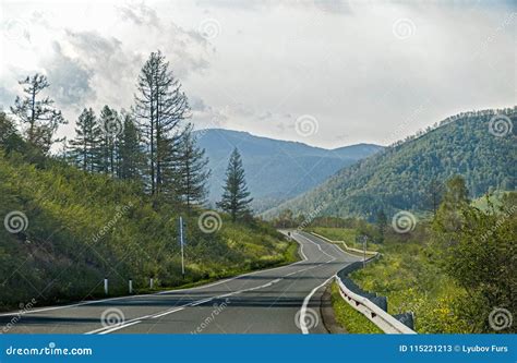 Highway Through Hilly Terrain With Trees And Clouds On Blue Sky Stock