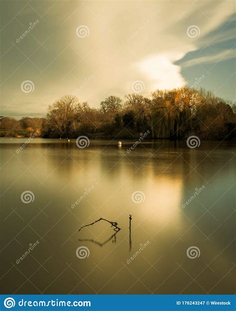 Vertical Picture Of A Lake Surrounded By Trees Under A Cloudy Sky