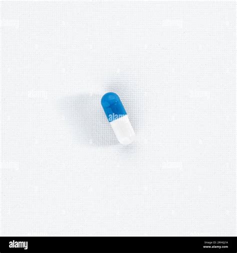 Blue white capsule pill on white textured background. Healthcare and