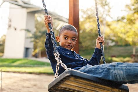 Black Boy Playing On A Playground Swing Del Colaborador De Stocksy