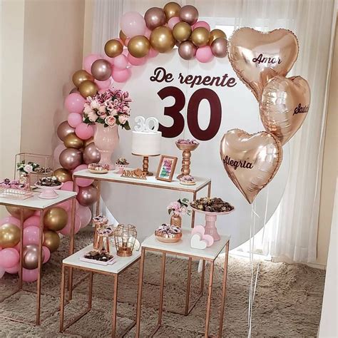 A Table Topped With Lots Of Pink And Gold Balloons Next To A Sign That