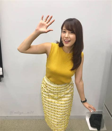 A Woman In A Yellow Top And Skirt Posing For The Camera With Her Hand Up