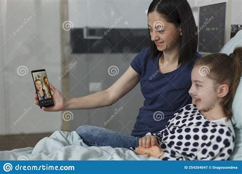 mother and sick daughter talking on smartphone virtual videocall with best friend stock image