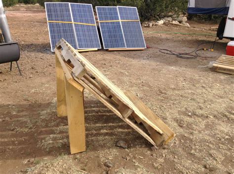 Two Solar Panels Sitting On Top Of A Wooden Structure In The Dirt Next